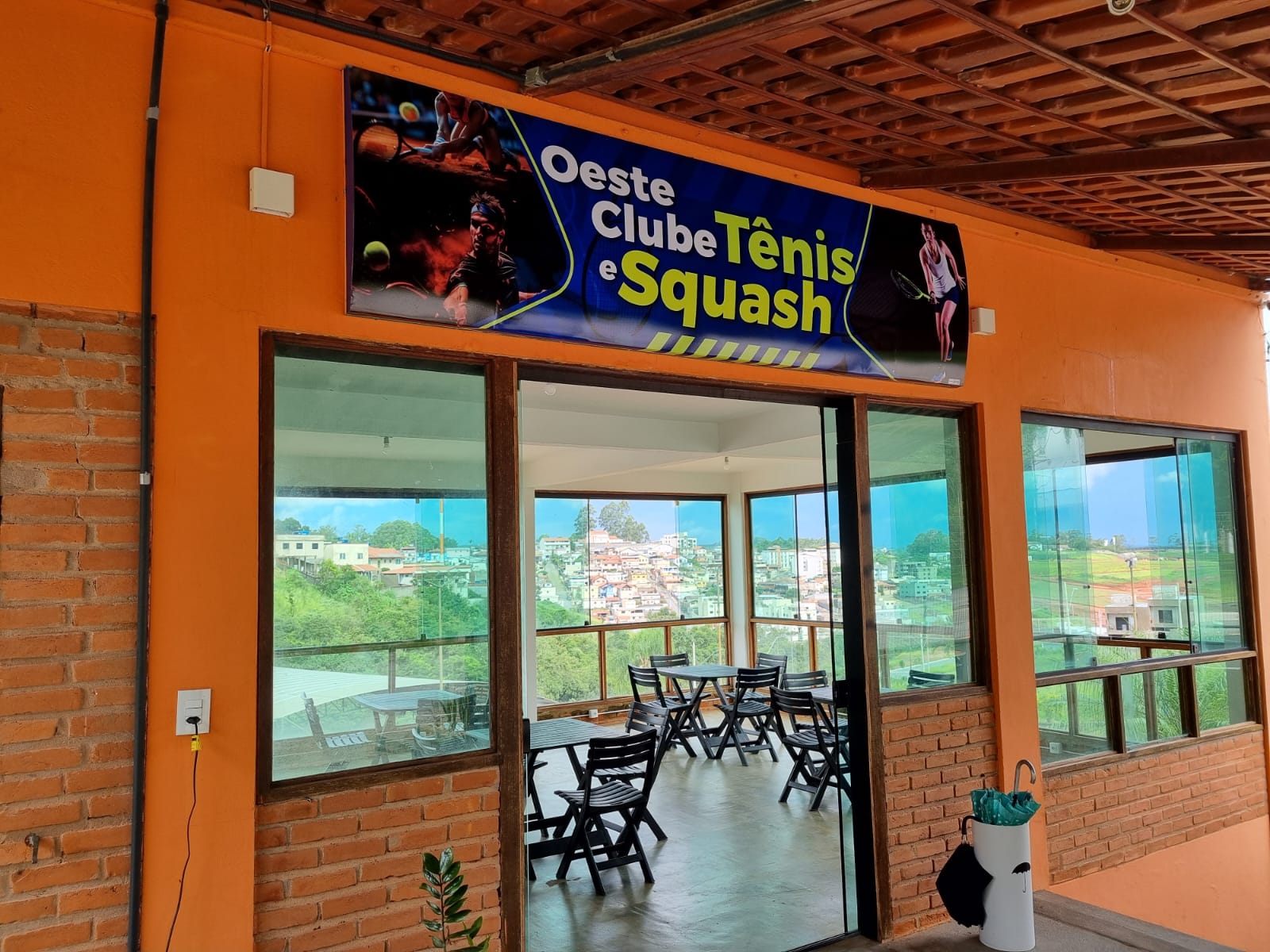Entrada da lanchonete do Oeste Clube com letreiro 'Oeste Clube e Tênis Squash'