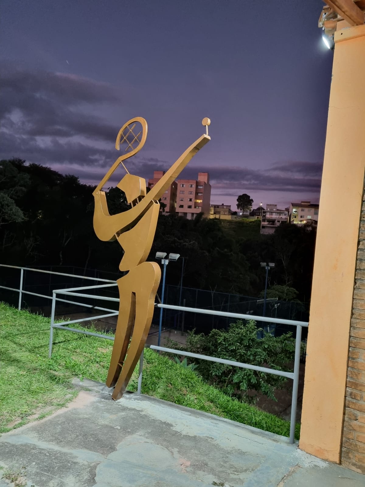 Escultura dourada do tenista, símbolo do Oeste Clube, ao entardecer