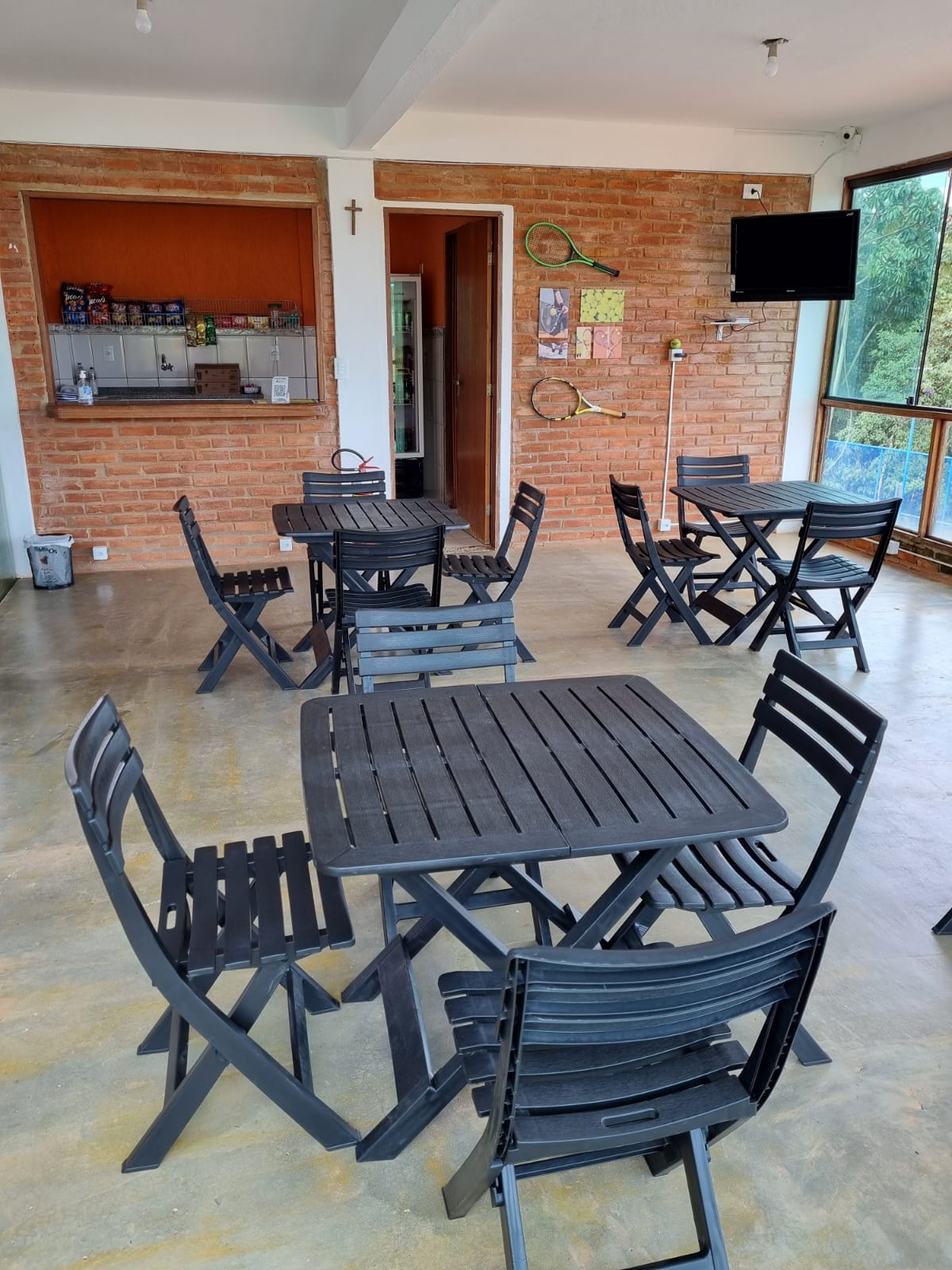 Salão da lanchonete do Oeste Clube com mesas e vista para as quadras